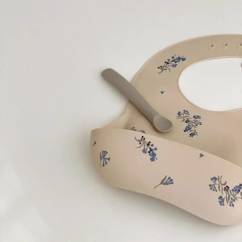 Waterproof silicone baby bib with cute floral pattern, adjustable for toddlers aged 1-3 years.