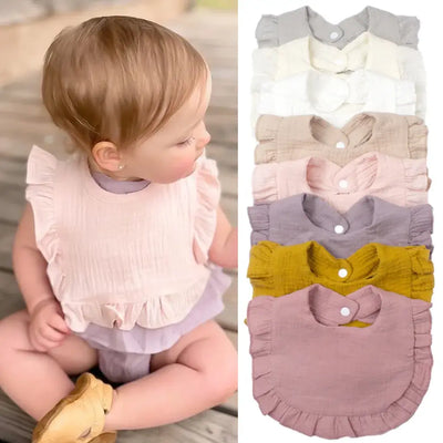 Cute baby wearing a pink gauze bib; showcasing a variety of solid color options in cotton with ruffle edges.