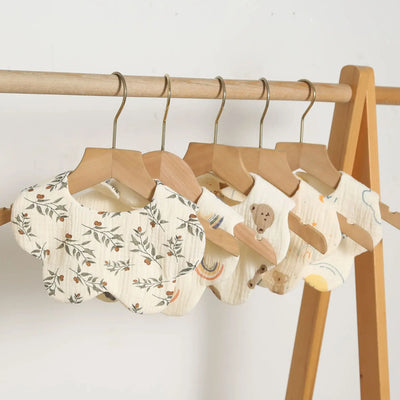 Newborn baby bibs hanging on a rack, featuring floral patterns and playful designs, perfect for infants and toddlers.