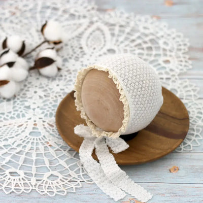 Newborn photography prop: cute white waffle lace tie hat for infants aged 0-6 months on wooden plate, featuring cotton decor.