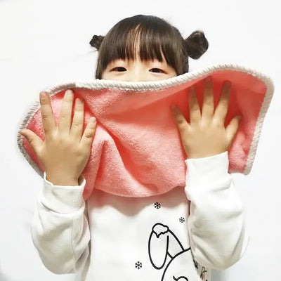 Child holding a soft pink baby bib, playfully pretending to wash her face, great for learning brushing teeth.