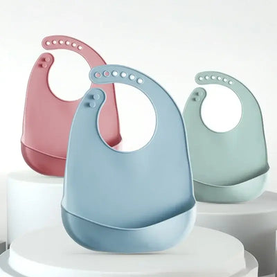 Set of three adjustable waterproof silicone baby bibs in pastel colors on a display.