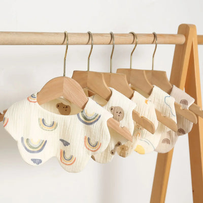Set of cute cotton baby bibs on hangers featuring bear and rainbow designs, perfect for feeding and drooling infants.
