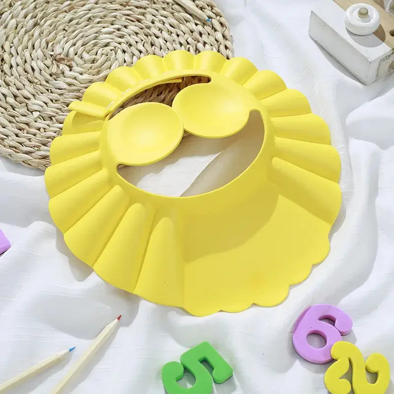 Yellow baby shower cap, adjustable and soft, designed for safe hair washing and ear protection during bath time.