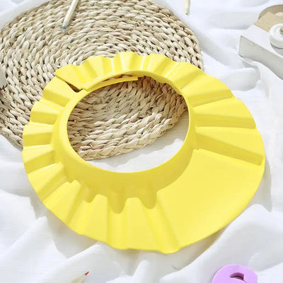 Yellow adjustable baby shower cap for kids, providing ear protection and comfort during hair washing.