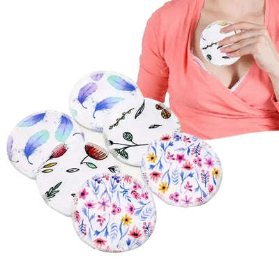 6 washable bamboo nursing pads with floral designs held by a breastfeeding mother in a pink shirt.